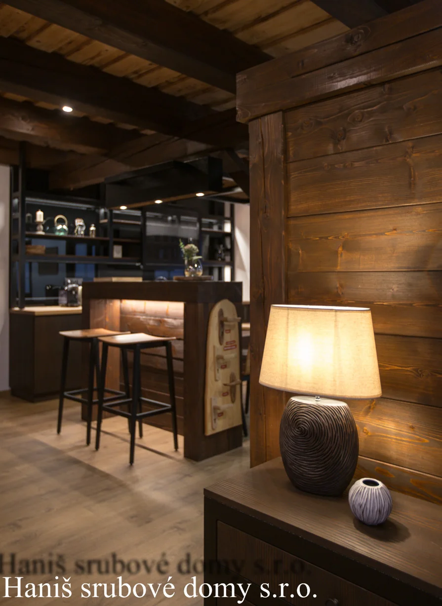 Barový pult se stoličkami a stolní lampa v interiéru showroomu Haniš