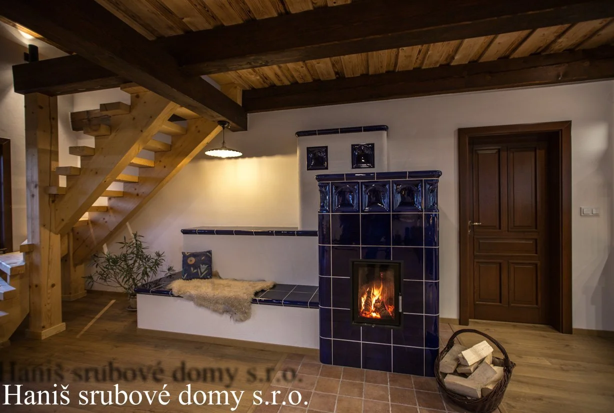Modrá kachlová kamna s hořícím ohněm u dřevěného schodiště