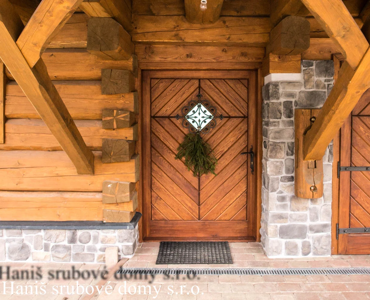 Detail vchodových dveří roubenky s kamenným obkladem a jehličím