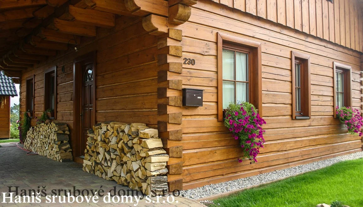 Detail srubové fasády s poštovní schránkou a naskládaným dřevem
